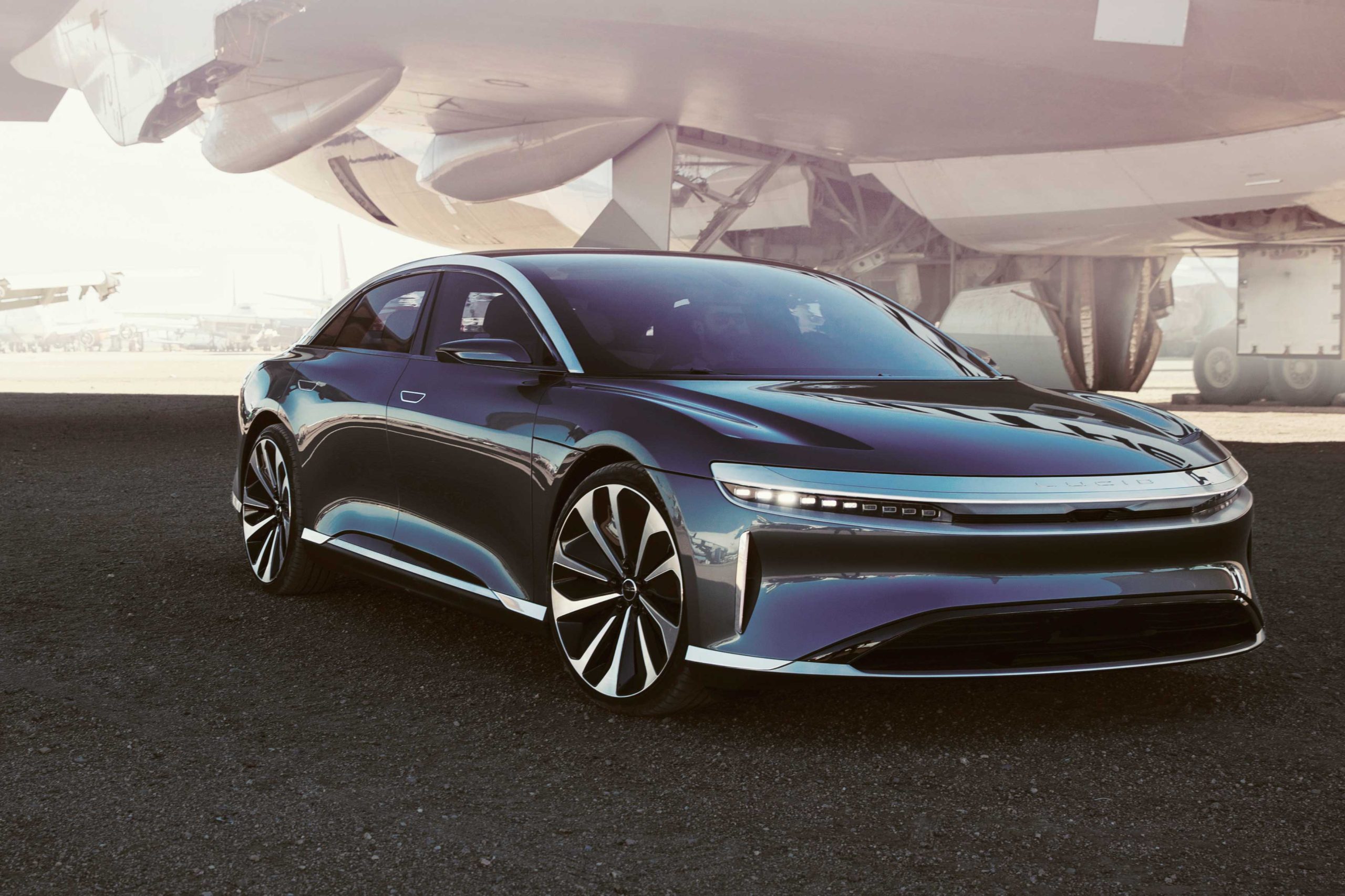 Artistic representation of the Lucid Air electric sedan in a futuristic cityscape at dusk.