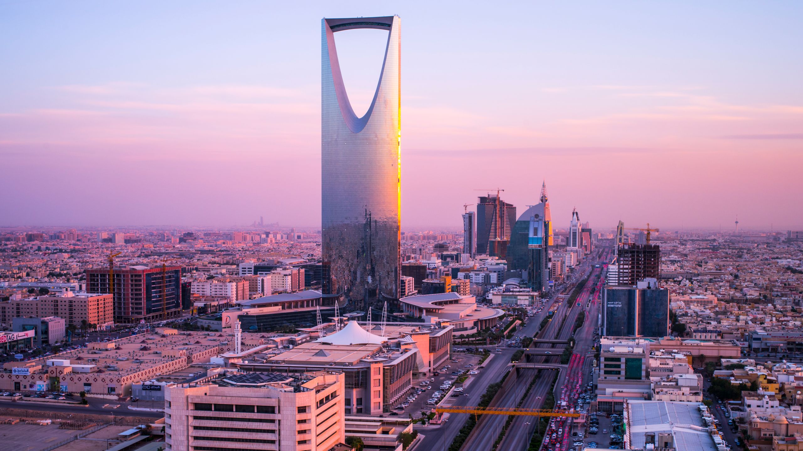 A vibrant modern cityscape in Saudi Arabia showcasing Pokemon GO gameplay with diverse gamers using smartphones.