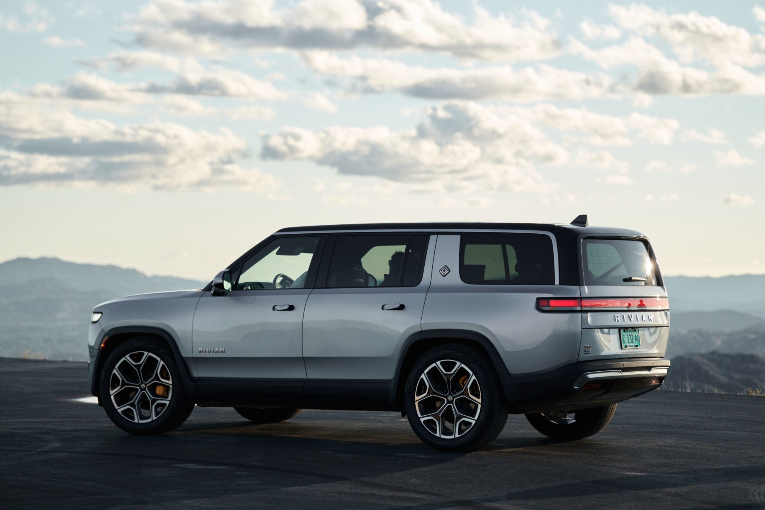 A futuristic Rivian electric vehicle with graphs indicating positive growth and profit for 2024 in a modern, eco-friendly setting.